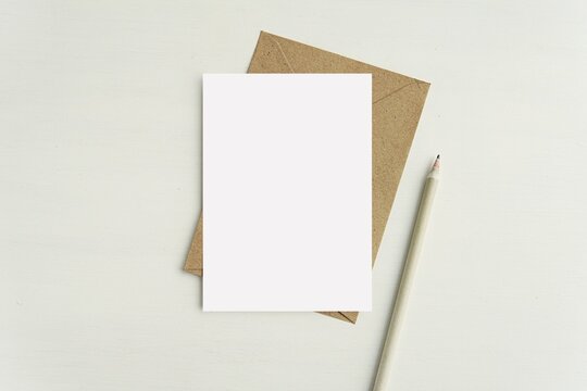 A6 card notecard, greeting card, postcard mockup for design presentation or text, brown envelope, pencil, minimal flat lay.