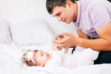 a newborn girl is lying with her young father in a snow-white bed. the concept of the family