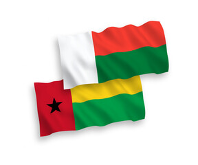 National vector fabric wave flags of Republic of Guinea Bissau and Madagascar isolated on white background. 1 to 2 proportion.