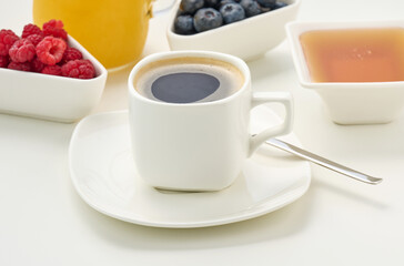 white ceramic cup with black coffee stands on a white table, breakfast