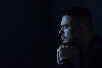 Portrait of a young dark-haired man with a beard in profile on a black background. The concept of...