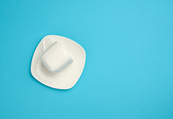 empty white ceramic cup and saucer on blue background, top view