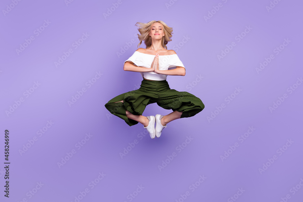 Wall mural Photo of lady jump meditate close eyes lotus pose wear white blouse flared trousers isolated purple color background