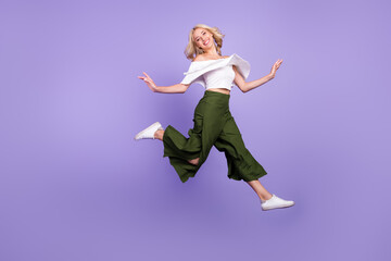 Photo of carefree lady jump go run wear white blouse flared trousers isolated violet color...