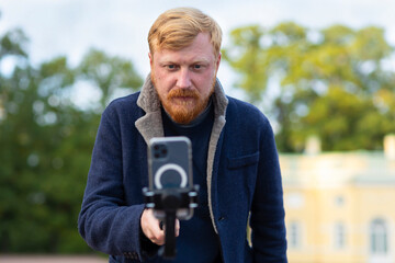 red haired photographer, videographer man with beard, mustache taking story, photo, video...
