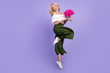 Photo of affectionate lady jump hold bouquet flowers wear white blouse flared trousers isolated violet color background