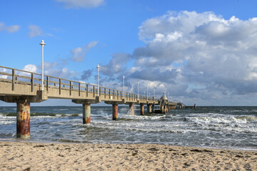 Seabridge at the beach in the tourist resort zinnowitz at the baltic sea, windy weather with waves on the water and blue sky with clouds, copy space