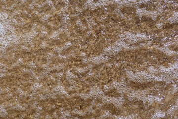 Wet sand on the beach as background. Sand and sea water with gentle sea foam