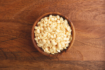 Wooden bowl of wax beans on wooden background. Top view. Hair removal, depilation.