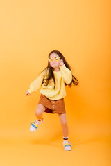 Close-up portrait of a cute little girl. Studio shot over yellow background. Childhood concept.