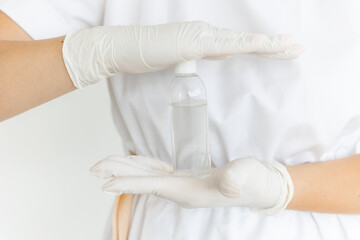 women's hands in white medical gloves hold a bottle of cosmetics. Liquid in a disposable bottle. Cosmetology and medical services office.