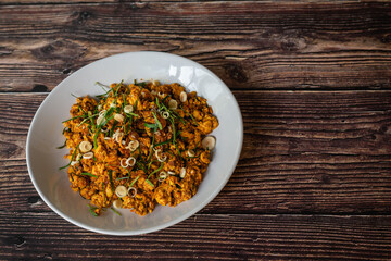Stir fried tofu with Thai spicy yellow curry for vegetarian food on wooden background 