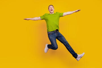 Fototapeta na wymiar Full length photo of nice attractive cheerful optimistic guy having fun jump up fly air plane isolated over yellow background