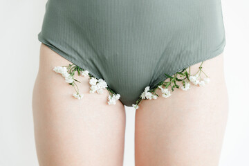 a part of the girl's body. white flowers stick out of his underpants. the concept of cosmetology...