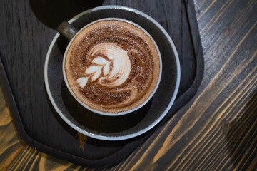 A cup of coffee latte art on the wooden table in coffee shop vintage style is the most popular drink for modern people.
