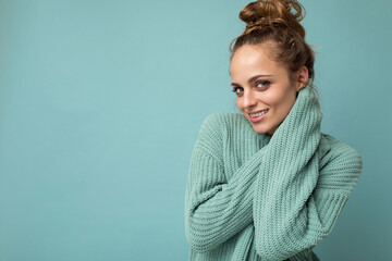 Obraz premium Young beautiful cute curly blonde woman with sexy expression, cheerful and happy face wearing trendy blue sweater isolated over blue background with copy space
