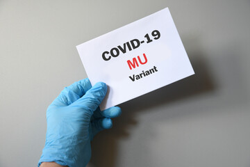 Doctor's hand in blue glove with white paper and text Covid-19 Mu Variant. Concept of medical variety Mu variant and COVID-19. Concept words 'mu variant'. COVID-19 mu variant concept.