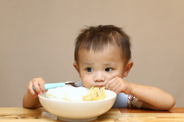 泣きながらパスタを食べる少年