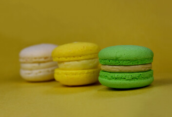 Green, yellow and white macarons on a yellow background stock images. Delicious french macarons isolated on a yellow background with copy space for text