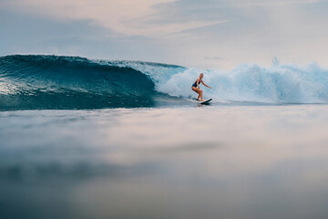 Surfgirl at surfboard and perfect barrel wave. Sporty woman during surfing.