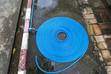 Blue plastic water pipe arrange in round shape on old cement floor, cleaning and garden equipment