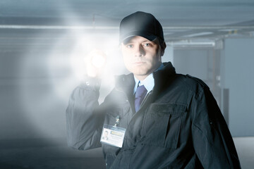 Security guard with flashlight at door in empty parking garage - obrazy, fototapety, plakaty