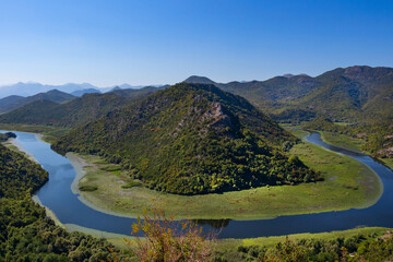 Fototapeta na wymiar Breathtaking view of the Crnojevica river canyon from the Pavlova Strana Viewpoint, Lake Skadar, Montenegro. The place where the river bends in a horseshoe shape around a green mountain