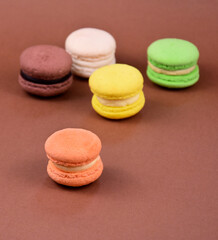 Colorful macarons on a brown background stock images. Colored french macarons isolated on a brown background with copy space for text