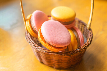 Sweet and bright strawberry and orange macarons in a gift basket. French dessert.