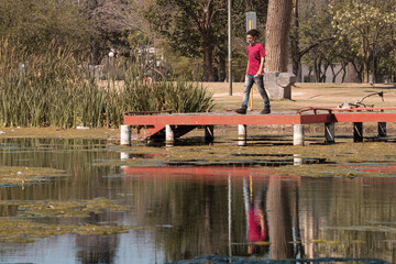 Hombre caminando por el muelle del lago en un parque