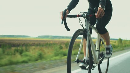 Professional female triathlete in protective helmet and sunglasses cycling on road while preparing for triathlon race