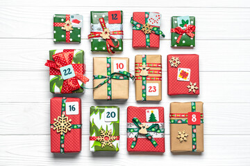 Handmade wrapped red, green gift boxes decorated with ribbons, snowflakes and numbers, Christmas decorations and decor on white table Xmas advent calendar concept Top view Flat lay Holiday card