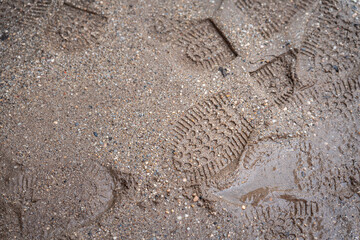 Safety boots footstep imprint on wet mud at construction working site location.