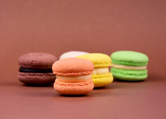 Colorful macarons on a brown background stock images. Colored french macarons isolated on a brown background with copy space for text