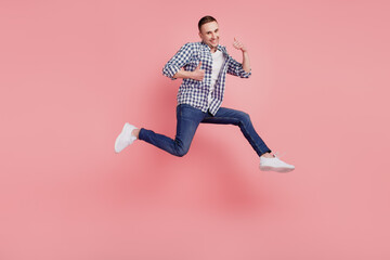 Fototapeta na wymiar Full length photo of young guy happy positive smile jumping show thumb-up isolated on pink color background