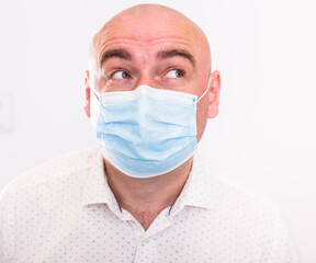 portrait of bald adult elderly man in medical mask with emotions on white background