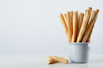 Delicious grissini sticks on white wooden table. Space for text
