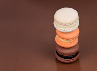 Pile of white, orange, brown, macarons on a brown background frame stock images. Delicious french macarons isolated on a brown background with copy space for text