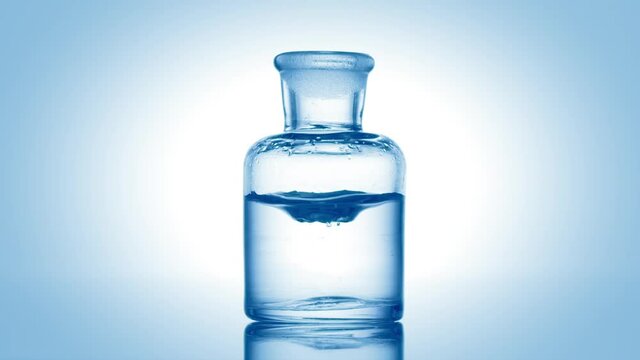 Blue drop is falling into old fashioned bottle with blue clear fluid on pale blue background | Abstract skincare cosmetics with hypochlorous acid mixing concept