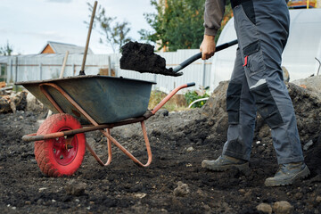 Working with garden tools, shovel and wheelbarrow on the site of a country house. Preparation for construction work.