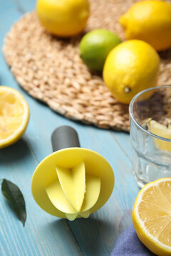 Citrus reamer and fresh lemons on light blue wooden table
