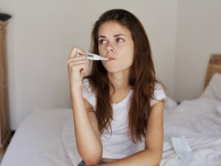 woman with a thermometer in her mouth waiting for the temperature result