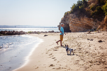 Beautiful young boy and dog walking together on the beach