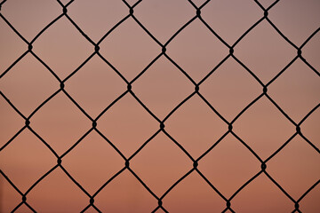 Naklejka premium Close-up of wire fence, sunset background, concept of freedom