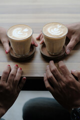 two person holding a cup of coffee and capucino