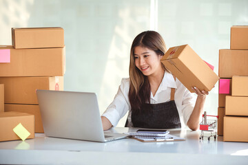 Small start-up business owners using computers at work, freelancers, saleswoman, checking production orders. Pack products for delivery to customers