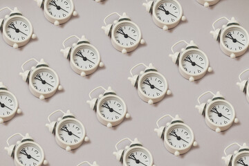 Seamless trendy pattern made of white retro alarm clock showing five minutes to twelve o'clock on gray paper background with copy space. Flat lay. Negative space.