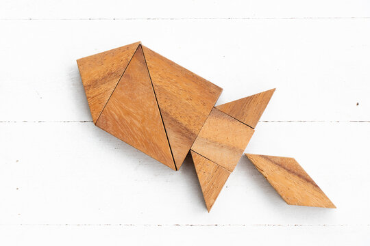 Wood tangram puzzle in rocket or missile shape on white wood background