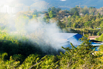 The image of smoke rising from the houses of people in the midst of nature.
