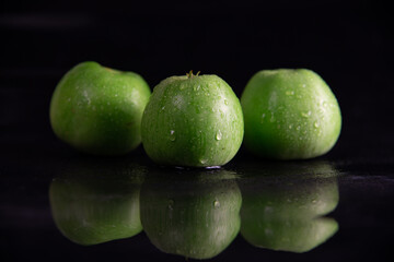fresh juicy green apples, in drops of dew on a black background